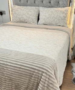 Dormitorio elegante con cama vestida con el edredón Sherpa Anabella de Dolz, que combina una textura aterciopelada con diseño floral en la parte superior y tejido tipo borreguito en la inferio